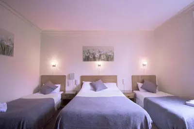 a room with two beds and two paintings on the wall at Pinegrove Hotel in Carlisle