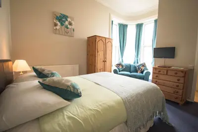 a bedroom with a bed with pillows and a chair at Pinegrove Hotel in Carlisle