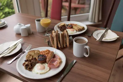 two plates of breakfast food on a wooden table at Pinegrove Hotel in Carlisle