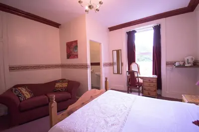 a bedroom with a bed and a couch and a window at Pinegrove Hotel in Carlisle