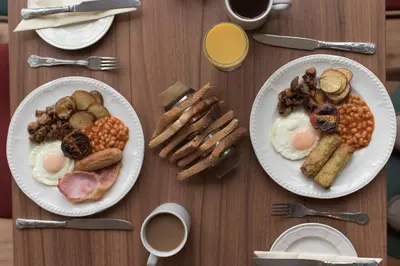 two plates of breakfast food on a wooden table at Pinegrove Hotel in Carlisle