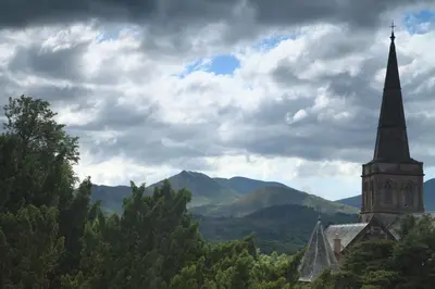 a church with a steeple and mountains in the background at Strathmore Guest House in Keswick