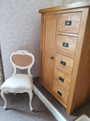 a white chair sitting next to a wooden dresser at Strathmore Guest House in Keswick