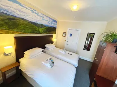 two beds in a room with a painting on the wall at Buccleuch Arms Hotel in Moffat