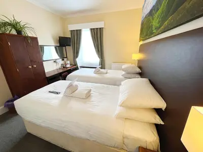 a hotel room with two beds with white pillows at Buccleuch Arms Hotel in Moffat