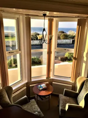 a room with three windows with a view of the ocean at Westcliff in Seascale