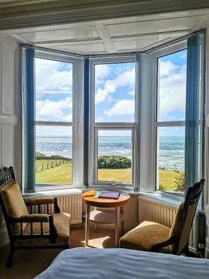 a bedroom with a bed and a table and windows at Westcliff in Seascale