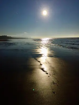 a sunset on a beach with footprints in the sand at Westcliff in Seascale