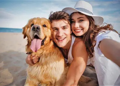 a man and a woman holding a dog on the beach at Ryan Bay Holiday Park in Innermessan