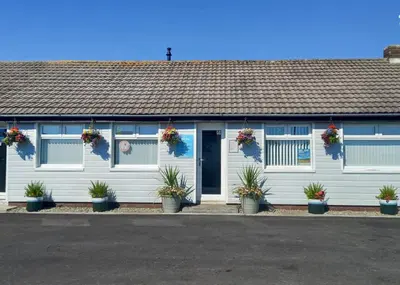 a white building with potted plants in front of it at Ryan Bay Holiday Park in Innermessan
