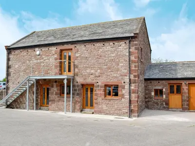 an old brick building with orange doors and windows at The Byres Tethera in St Bees
