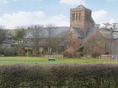 a large brick building with a tower and a church at The Byres Tethera in St Bees