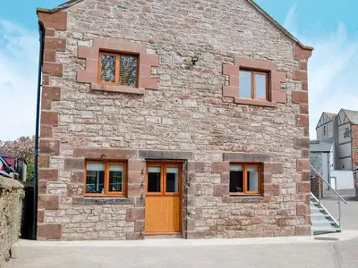 a brick building with orange doors and windows at The Byres Tethera in St Bees
