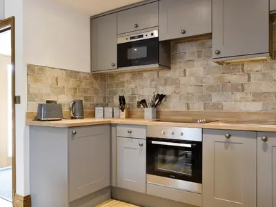 a kitchen with white cabinets and a stove top oven at The Byres Methera in St Bees