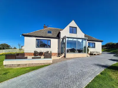a white house with large glass windows on a driveway at Gullsway in Glencaple