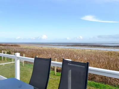 two chairs sitting on a fence next to the beach at Beachcomber Lodge in Mainsriddle