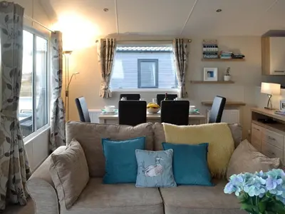 a living room with a couch with blue pillows at Beachcomber Lodge in Mainsriddle