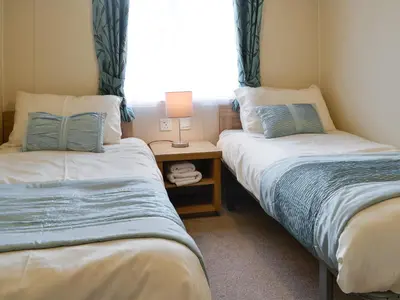 two beds in a room with a window at Beachcomber Lodge in Mainsriddle