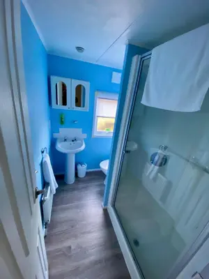 a blue bathroom with a shower and a sink at Limestone Lodges in Bothel