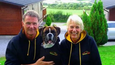 a man and a woman standing with a dog at Limestone Lodges in Bothel