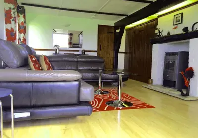 a living room with a leather couch and a fireplace at Limestone Lodges in Bothel