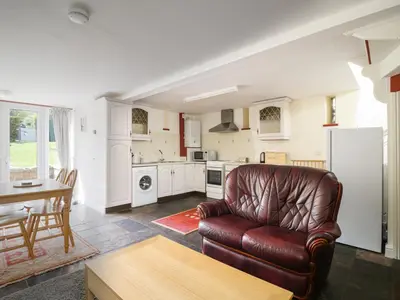 a living room with a leather couch and a kitchen at Swallows Nest in Carlisle