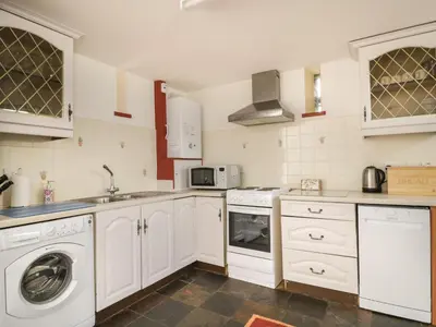 a kitchen with white cabinets and a washer at Swallows Nest in Carlisle