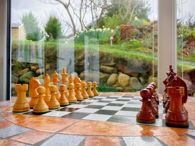 a chess set on a chessboard in front of a window at Romantic Quirky Cottage with private garden and parking in Beckermet
