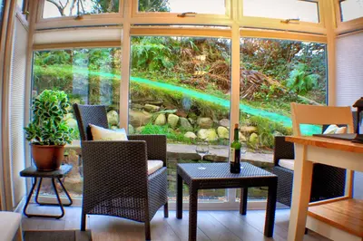 a room with a large window with a table and chairs at Romantic Quirky Cottage with private garden and parking in Beckermet