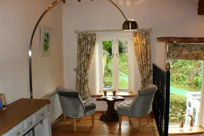 a living room with chairs and a large mirror at Romantic Quirky Cottage with private garden and parking in Beckermet