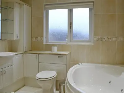 a bathroom with a tub and a toilet and a sink at Hawthorn Cottage in Stranraer