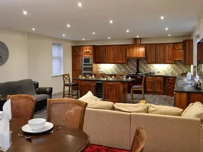 a living room with a couch and a kitchen at Liftingstane Farmhouse in Closeburn