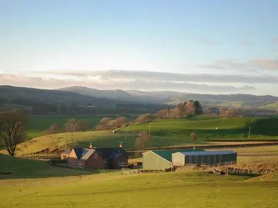 a farm with a barn in the middle of a field at Liftingstane Farmhouse in Closeburn