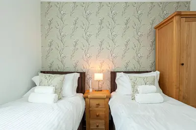 two twin beds in a bedroom with a wall mural at Carlton 2 a large modern Keswick appt with parking in Keswick