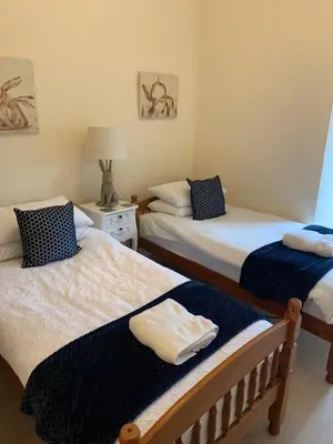 a bedroom with two beds and a table with a lamp at Home with a view in Moffat