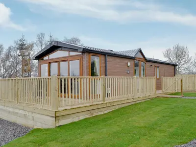 a house with a wooden fence in front of a yard at Skylark Lodge in Westward