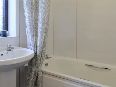 a bathroom with a sink and a shower curtain at Beuchan Bungalow in Closeburn