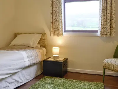 a bedroom with a bed with a lamp and a window at Beuchan Bungalow in Closeburn