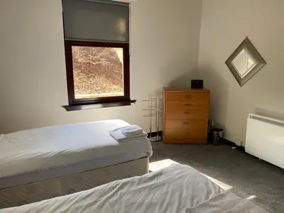 a bedroom with two beds and a dresser and a window at Welltrees Apartments 10 Dailly Road in Maybole