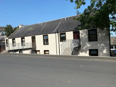 a white building with a black roof and stairs at Welltrees Apartments 14 Dailly Road Maybole in Maybole