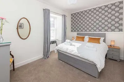 a bedroom with a large bed and a mirror at Maxwelston Farmhouse in Girvan