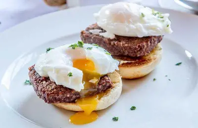 a plate with two breakfast sandwiches with eggs on top at Maxwelston Farmhouse in Girvan