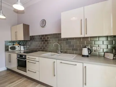 a kitchen with white cabinets and a sink at Ayr Beach View Apartment in Ayr