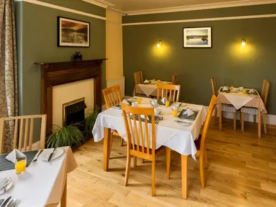 a dining room with tables and chairs and a fireplace at Craglands Guest House in Keswick