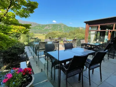 a patio with tables and chairs and mountains in the background at The Mary Mount Hotel in Keswick