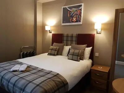a hotel room with a large bed with pillows at The Fairburn Hotel in Mauchline