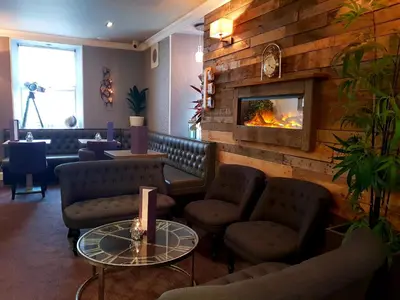 a lobby with a fireplace and couches and a table at The Fairburn Hotel in Mauchline