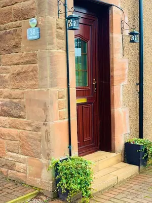 a red door on a brick building with a stairs at Private Apartment in Dumfries