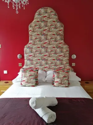 a bedroom with a large bed with a red wall at Allerdale Guest House in Keswick