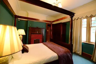 a bedroom with green walls and a bed with a canopy at Rivendell in Dumfries